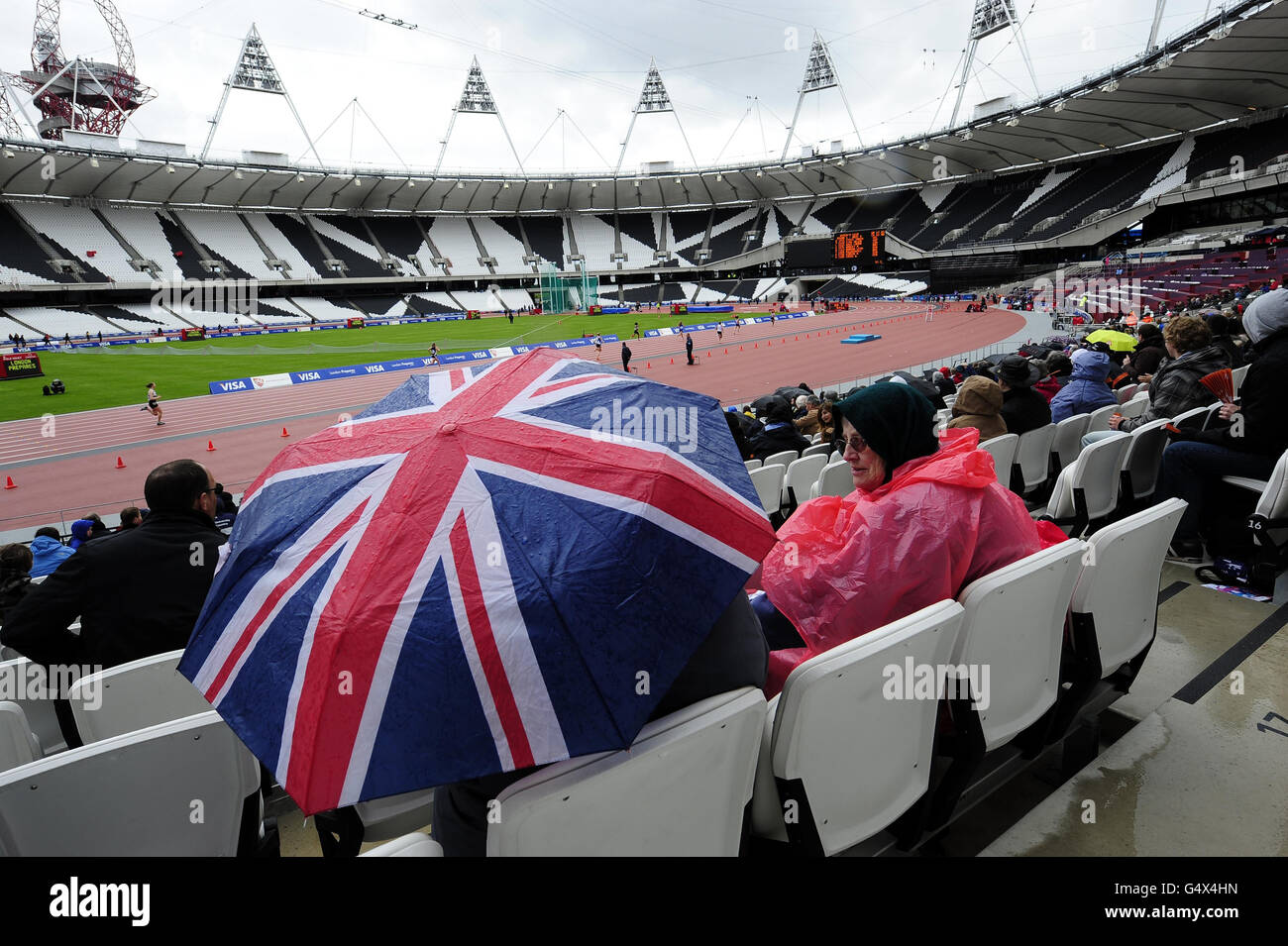 Les fans se réfugient à l'abri de la pluie lors des championnats sportifs des universités et collèges du stade olympique de Londres. Banque D'Images