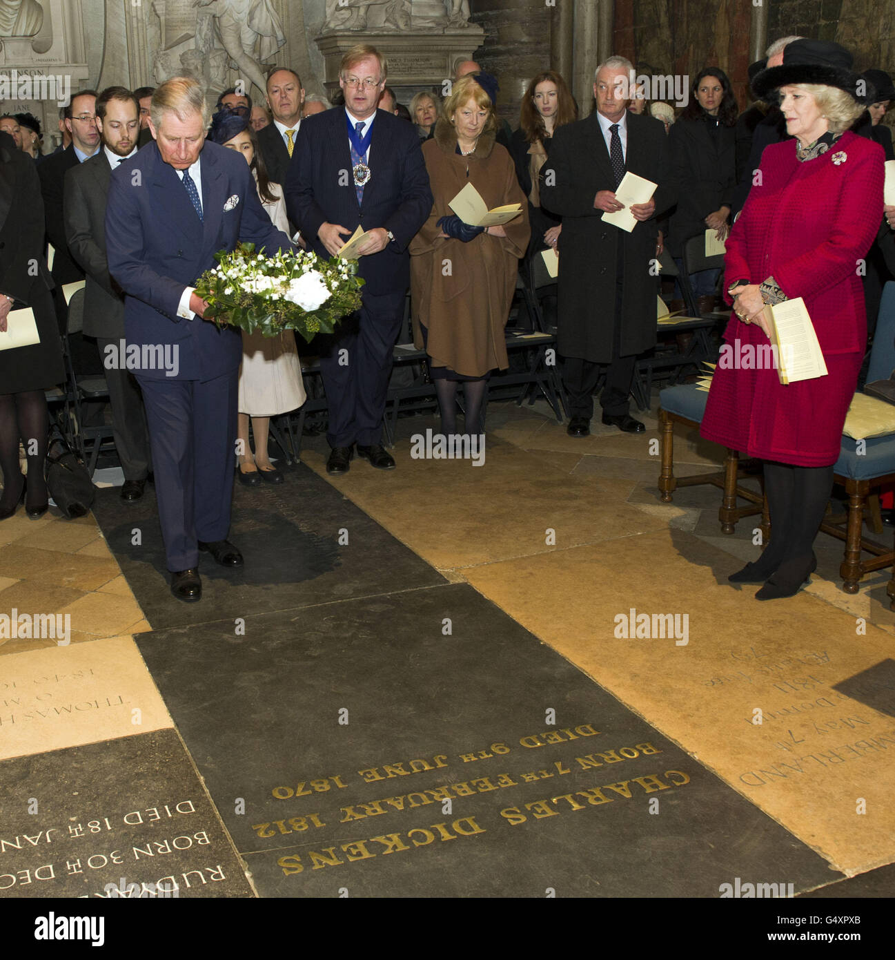 Le prince de Galles, observé par la duchesse de Cornouailles, dépose une couronne sur la tombe de Charles Dickens à l'abbaye de Westminster pour marquer le bicentenaire de la naissance de l'auteur. Banque D'Images