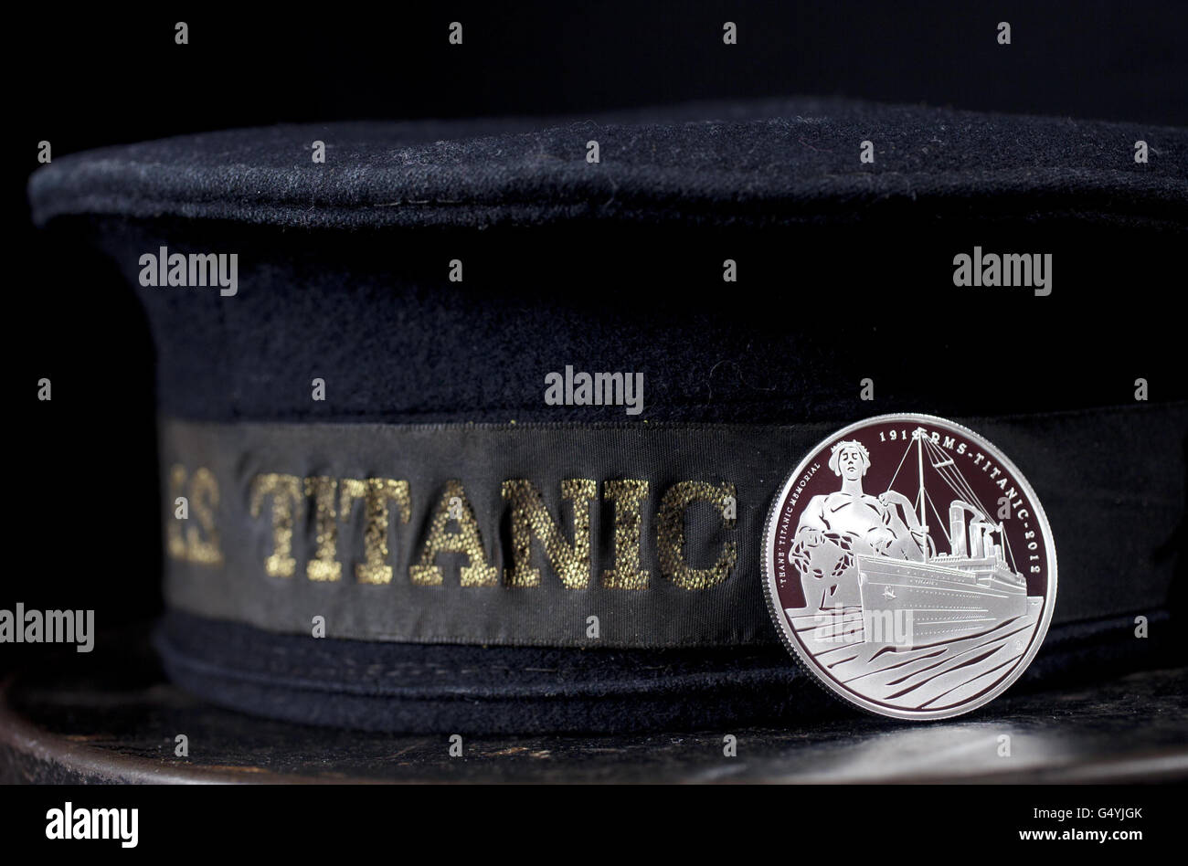 5 pièce en souvenir du 100e anniversaire du premier voyage de RMS Titanic repose contre le cap d'un équipier survivant. Banque D'Images