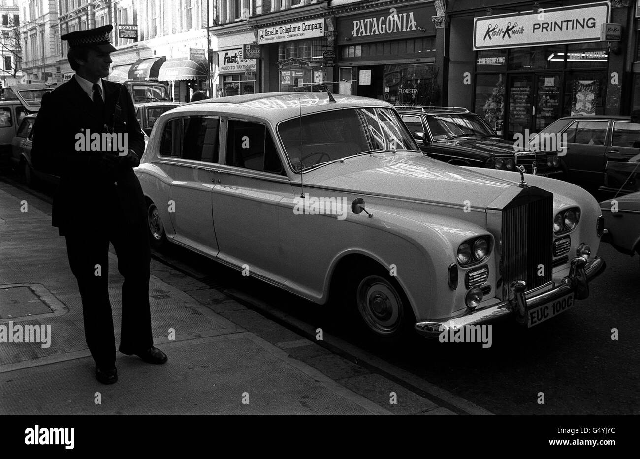 Un policier garde un œil sur une limousine blanche Phantom V Rolls Royce, qui appartenait à Beatle John Lennon et qui a reçu un billet de stationnement.La voiture et le billet, que Christies disent payer, seront mis aux enchères à l'aide des Samaritains. Banque D'Images