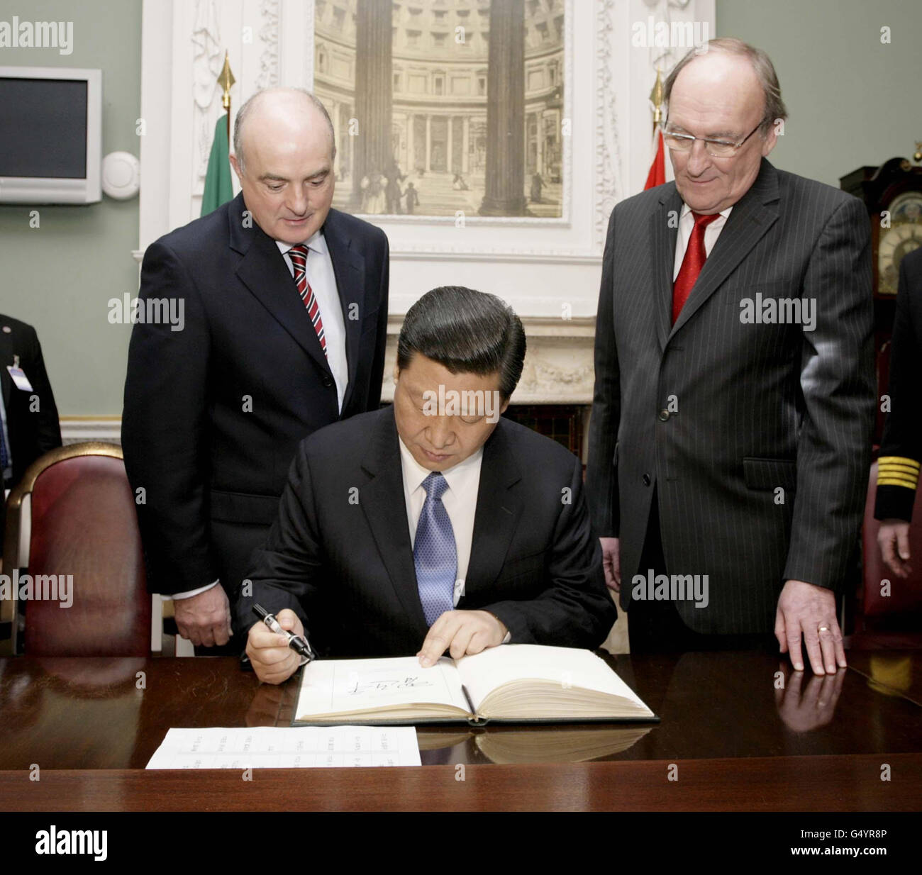 S.E. M. Xi Jinping , Vice-Président de la République populaire de Chine alors qu'il signe le livre des visiteurs avec en arrière-plan le sénateur Paddy Burke (à gauche) Cathaoirleach et M. Sean Barrett (à droite) T.D.Ceann Comhairle lorsque le vice-président a effectué une visite à Leinster House le troisième et dernier jour d'une visite de trois jours en Irlande. Banque D'Images