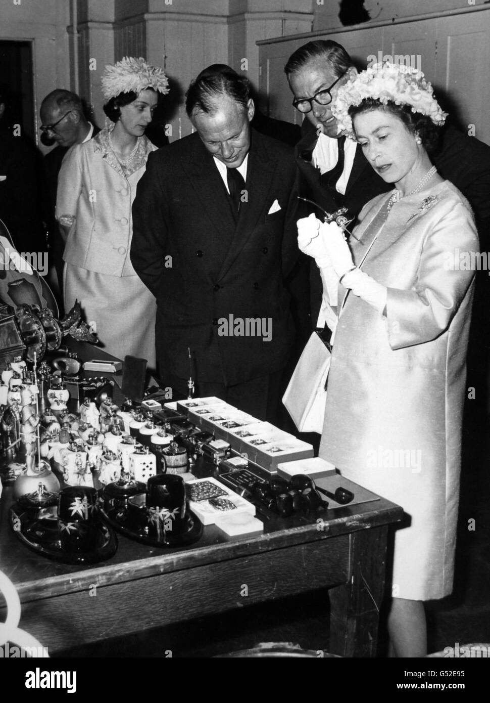 La reine Elizabeth II voit de près un briquet-appareil-photo lorsqu'on lui a montré des marchandises de contrebande, récemment saisies, après l'ouverture de l'aile est restaurée de la maison personnalisée dans la rue Lower Thames, ville de Londres. Banque D'Images