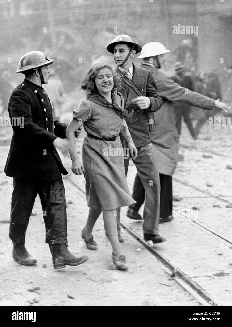 Une citadine qui sourit toujours après avoir été sauvée d'un bâtiment londonien qui venait d'être détruit par une bombe larguées par un raid allemand de la Luftwaffe. Banque D'Images