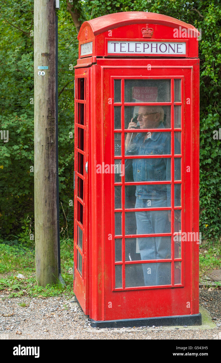 L'homme à l'aide d'un ancien style British téléphone rouge fort. Banque D'Images