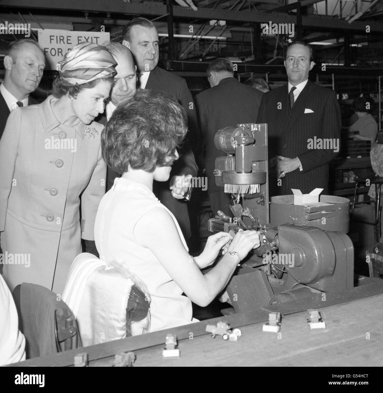 La reine Elizabeth II étudie attentivement un processus dans l'atelier d'emballage lors de sa visite chez les fabricants de la série de modèles « boîte à carton » - Lesney Products and Company Ltd - à Hackney Wick, Londres. Banque D'Images