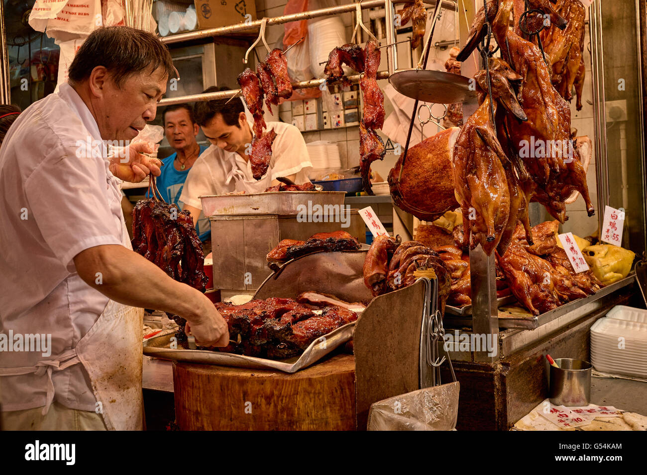 Un boucher prépare certaines cha-siu les aliments cuits à une boutique sur Shanghai Street à Yau Ma Tei, Hong Kong. Banque D'Images