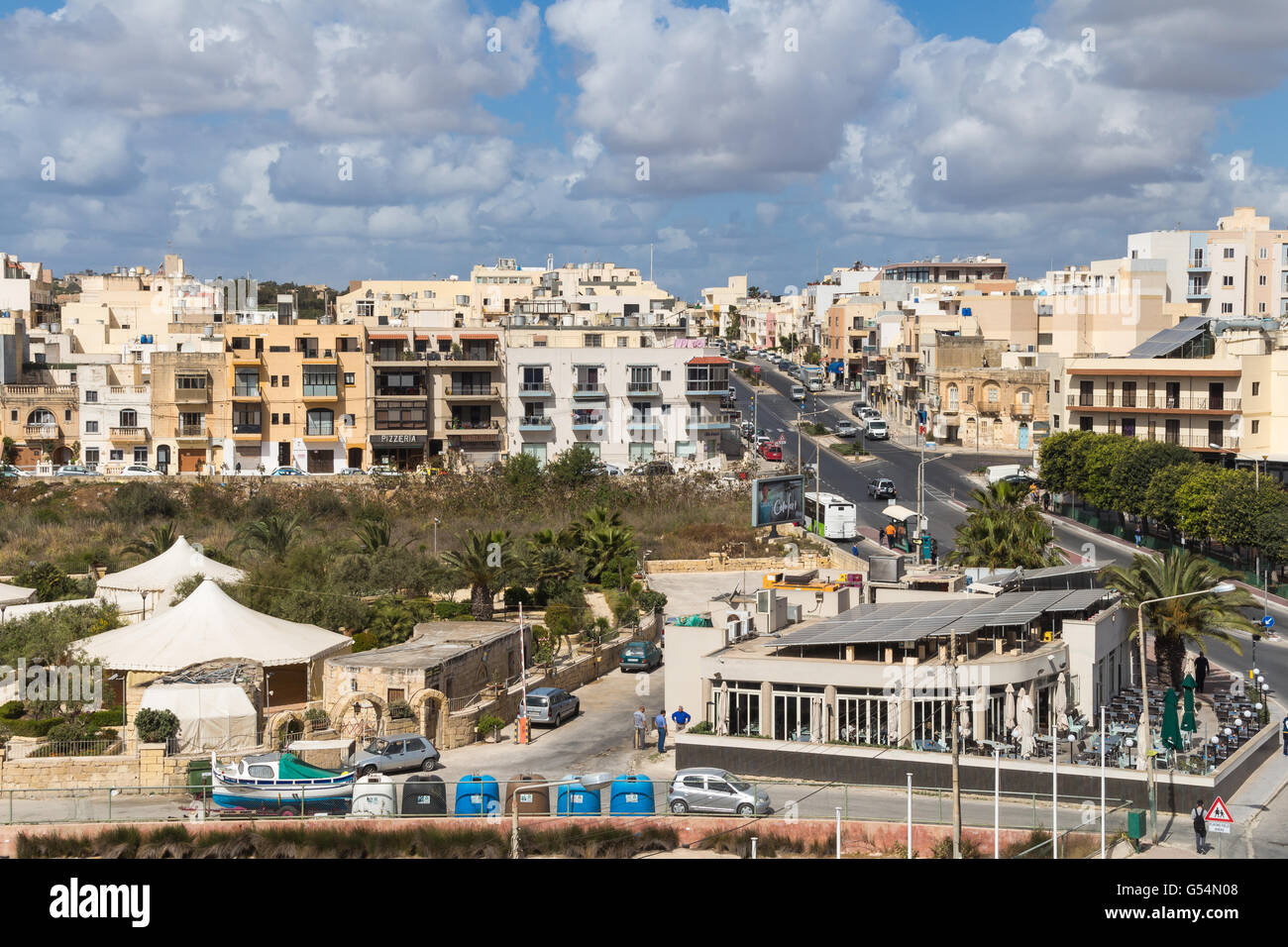 Marsascala ville sur l'île de Malte. Maisons d'habitation et d'une route avec des voitures. De nombreux nuages sur le ciel bleu. Banque D'Images