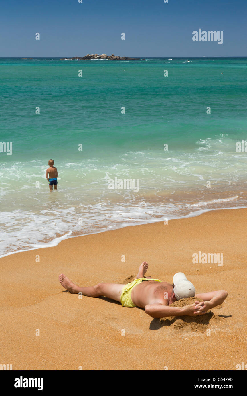 Sri Lanka, Galle Province, Unawatuna beach, sur le sable et sunbather jeune garçon en bas-fonds Banque D'Images