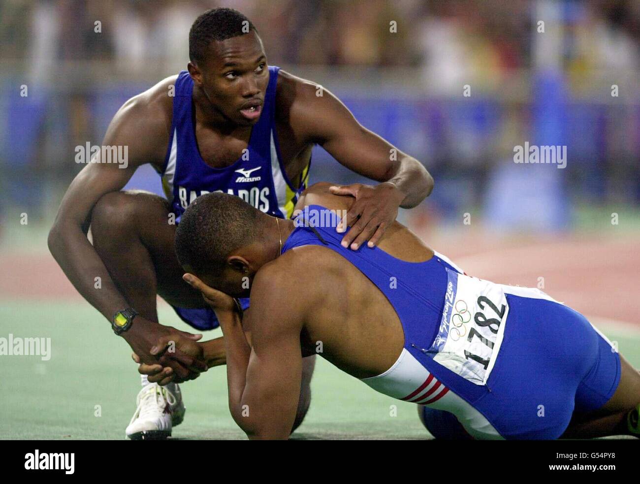 Darren Campbell, en Grande-Bretagne, est sur le plancher tandis que Obadele Thompson, de la Barbade, le félicite pour sa victoire de la médaille d'argent lors de la finale masculine de 200 m aux Jeux Olympiques de Sydney. Banque D'Images