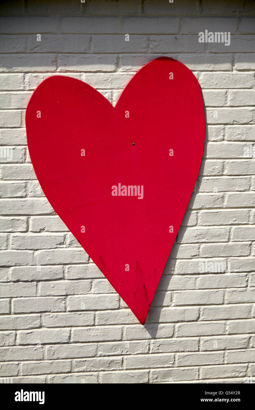 Hart rouge peint sur le mur de brique sur un jardin Banque D'Images