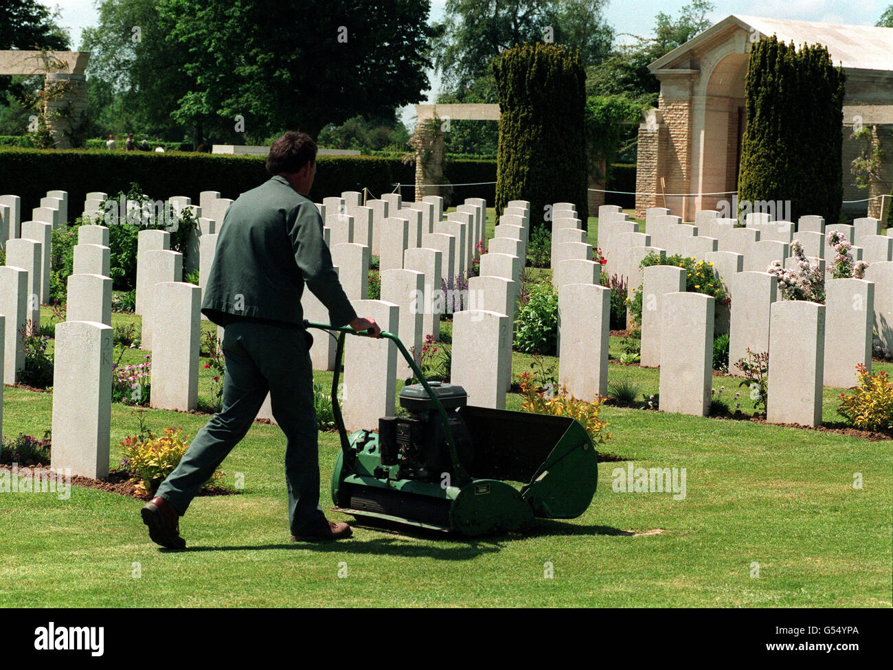 TOMBES DE GUERRE DU COMMONWEALTH : un jardinier tond les pelouses du cimetière militaire britannique de Bayeux, en Normandie. Le cimetière sera visité par la Reine à l'occasion du 50e anniversaire des Landes du jour J de juin 1944. La Normandie a été le théâtre de violents combats entre les forces alliées et allemandes pendant la Seconde Guerre mondiale. * 11/11/2000 jardinier fauchant les pelouses au cimetière militaire britannique de Bayeux, en Normandie. Des menaces de réduction des salaires pour les jardiniers qui ont tendance à entretenir les charniers britanniques à l'étranger ont été mises en attente pendant qu'un examen des allocations a été effectué, ce qui a été confirmé samedi 11 novembre 2000. Le mouvement est un Banque D'Images