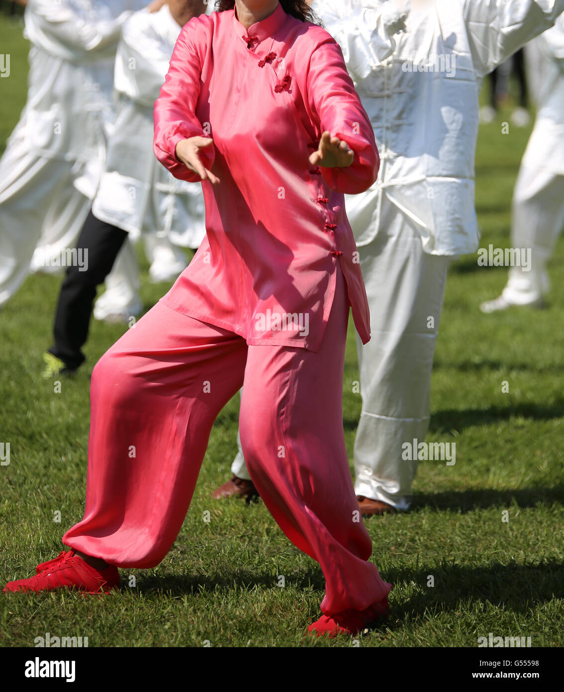L'art martial Femme avec robe de soie rose parfaitement exécuter les exercices dans le grand parc public Banque D'Images