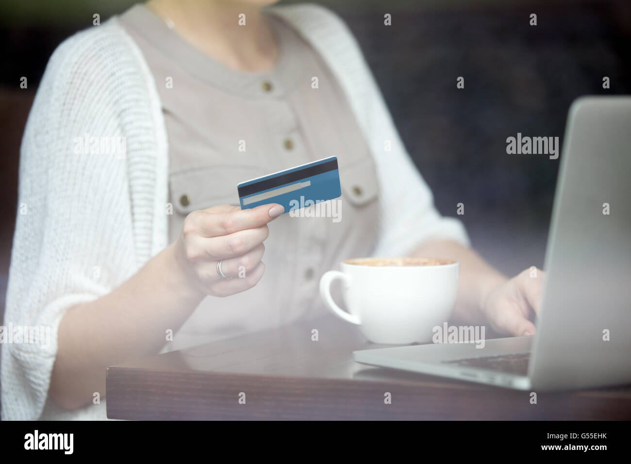 Belle Jeune femme assise dans le café urbain moderne et de payer par carte de crédit pour faire des achats en ligne sur ordinateur portable Banque D'Images