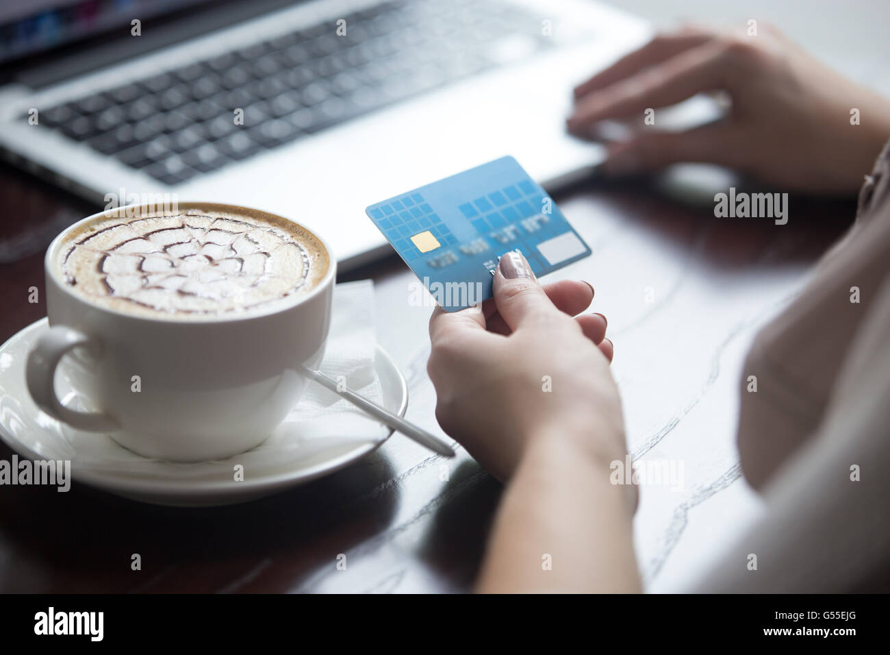 Belle Jeune femme assise dans un café cappuccino potable urbaine moderne et de payer par carte de crédit pour faire des achats en ligne Banque D'Images