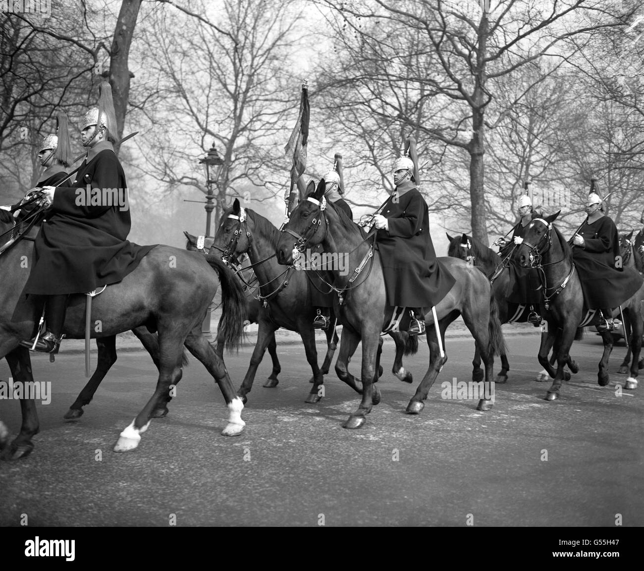 Couleurs drapées de noir, en deuil pour la reine Mary, portée par un détachement de Household Cavalry dans le Mall, Londres. Banque D'Images