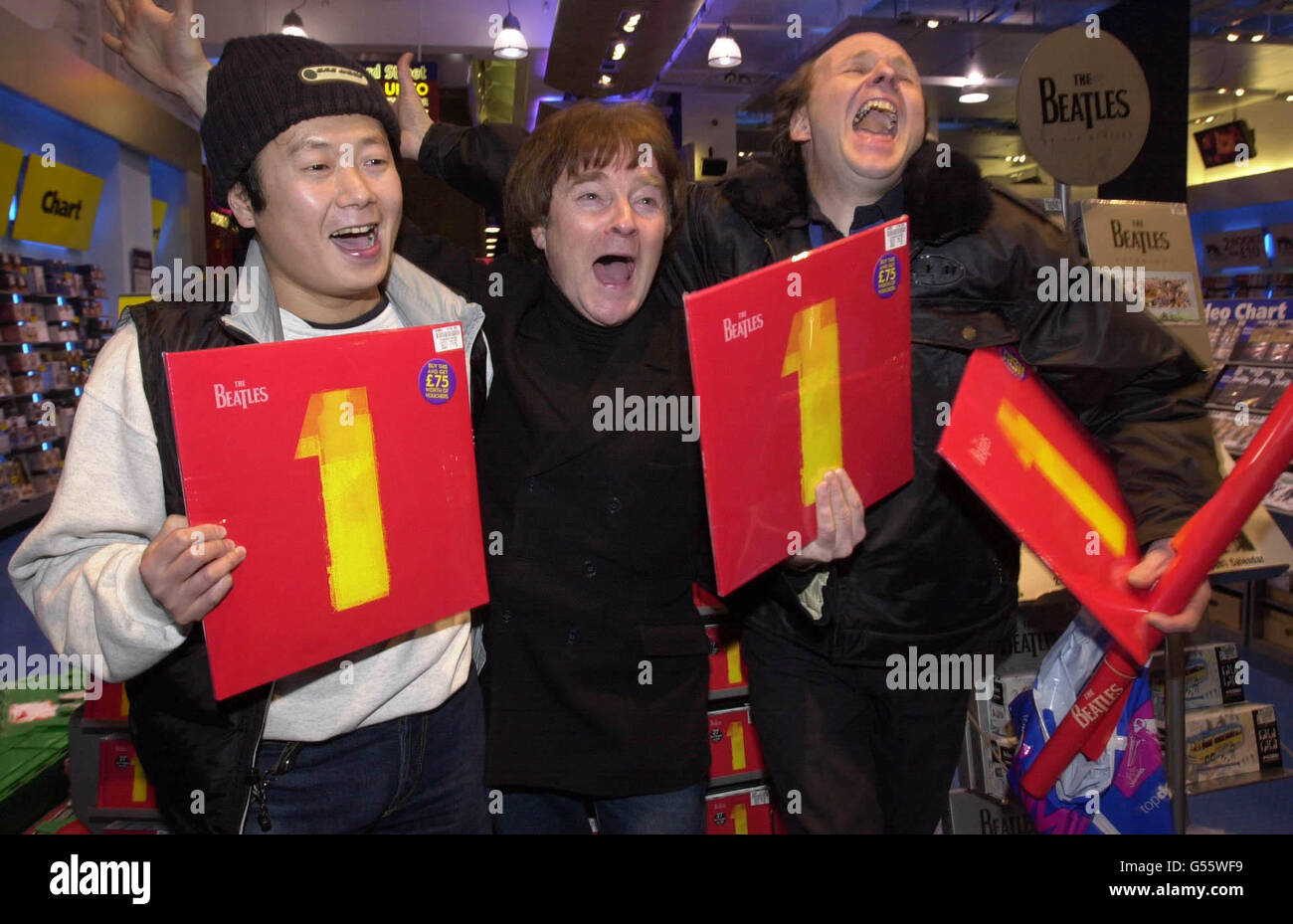 Les fans de Beatles,(L-R) Naoto Ito, Alan Harrington et Geoff Evans montrent leur plaisir à HMV à Oxford Street, Londres, à une minute après minuit, d'être l'un des premiers à acheter 1, un album de compilation de vingt-sept numéros un par les Beatles. * 24/11/00: Après avoir été en tête des classements de l'album britannique le 19/11/00, les Beatles lui ont fait un double dans le nouveau graphique du panneau d'affichage des États-Unis. Le bien nommé Beatles 1 a vendu 595,000 copies sa première semaine aux États-Unis pour battre la compilation maintenant que c'est ce que j'appelle musique 5 au premier rang. C'est maintenant l'album le plus vendu dans les 18 pays du monde qui compile un Banque D'Images