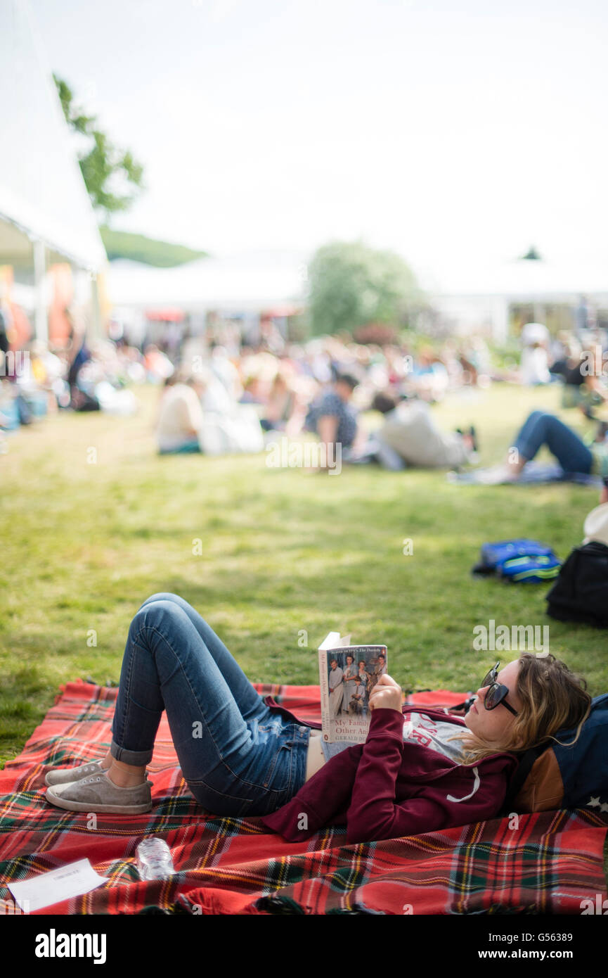 Une jeune femme, sur le gazon, la lecture de son livre à l'assemblée le Hay Festival de la littérature et les arts, "le Woodstock de l'esprit', Hay on Wye, Powys, Wales UK Mai-juin 2016 Banque D'Images