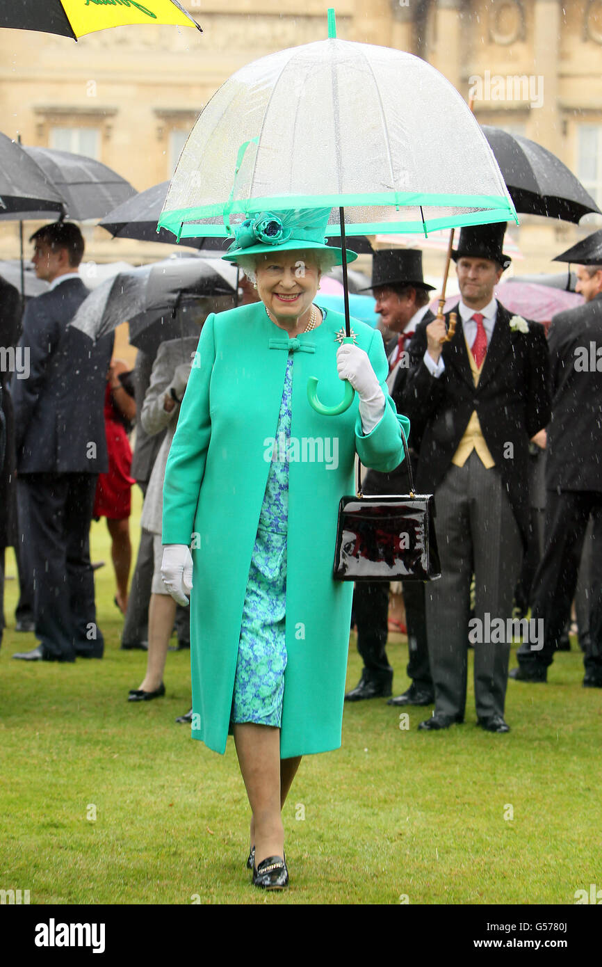 La reine Elizabeth II de Grande-Bretagne se protège de la pluie sous un  parapluie alors qu'elle organise une fête dans le jardin au palais de  Buckingham, dans le centre de Londres Photo