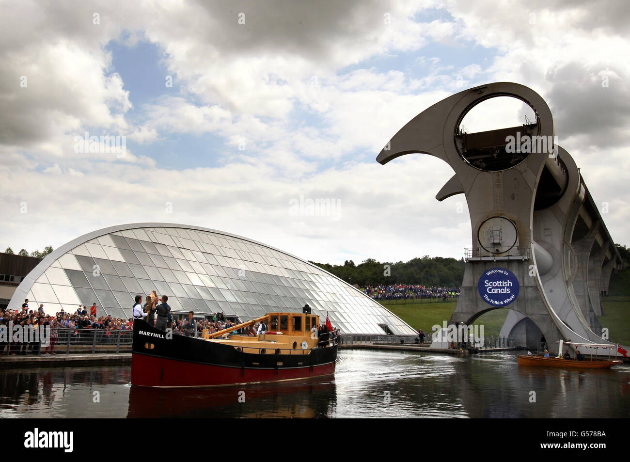 Le porteur de la flamme olympique Dennis May avec la flamme olympique sur un bateau à la roue Falkirk à Falkirk comme le relais de la flamme continue. Banque D'Images