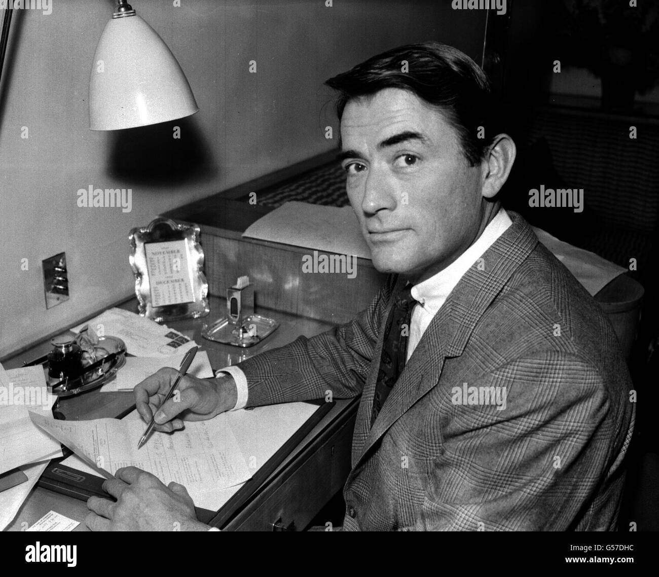 GREGORY PECK 1959: La star de cinéma américaine Gregory Peck, à son hôtel de Londres, rédige une demande de visa pour Moscou, Russie. Il est à Londres pour la première de son film 'On the Beach' à Leicester Square. Banque D'Images