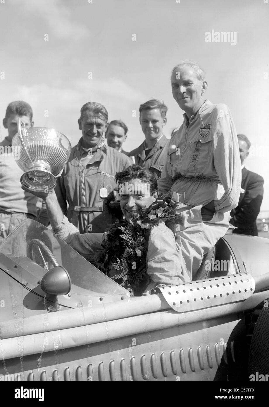 Portant la guirlande traditionnelle et tenant en altitude la coupe est Roy Salvadori, gagnant dans un Maserati de la course de télégraphe quotidien Trophée à Aintree. Banque D'Images