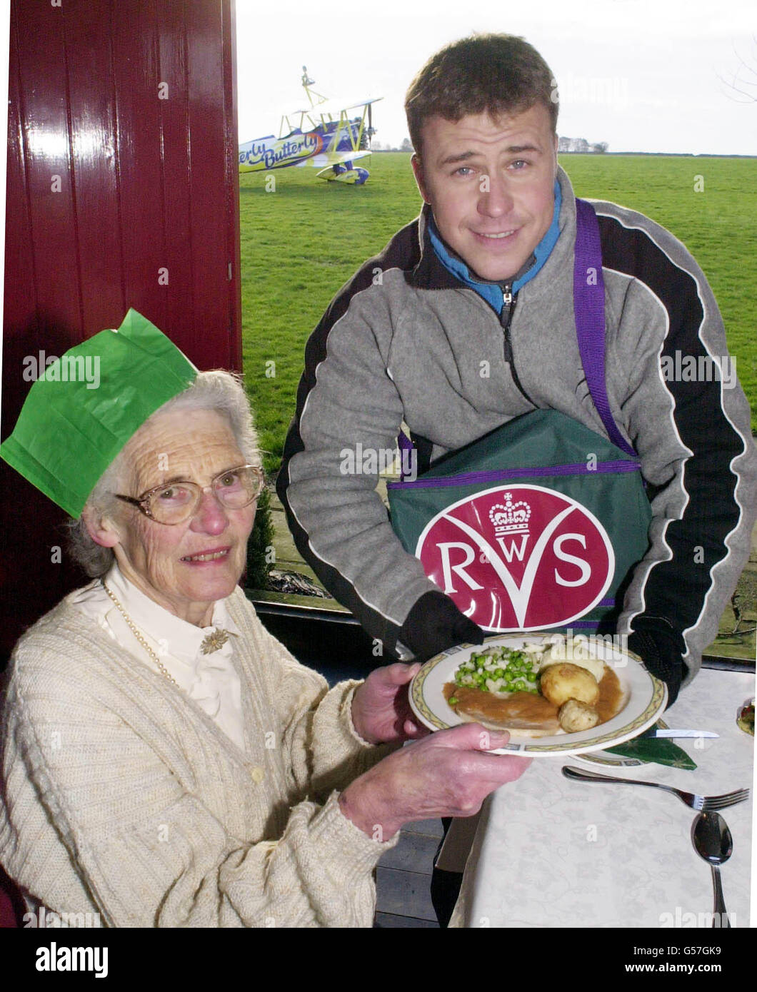 Craig Phillips, gagnant de Big Brother, livre un repas de service volontaire féminin à Betty Crowe, 76 ans, de Cirencester à l'aérodrome de Rendcomb, dans le Gloucestershire, après avoir effectué une promenade dans les ailes sur un Boeing 1940 bi-avion Staarman. * Craig a réalisé l'exploit pour rappeler aux gens que WRVS livrer des repas sur roues. Banque D'Images