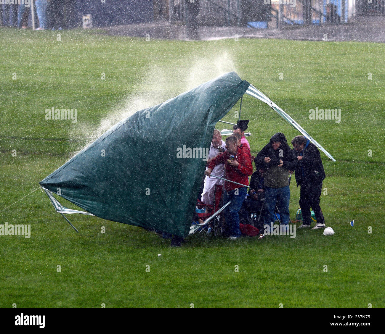 Une courte tempête de pluie balaie la Knavesmire et fait sauter cette tente tandis que les Racegoers tentent de se garder au sec à mi-été Raceday lors de la réunion de juin à York Racecourse, York. Banque D'Images