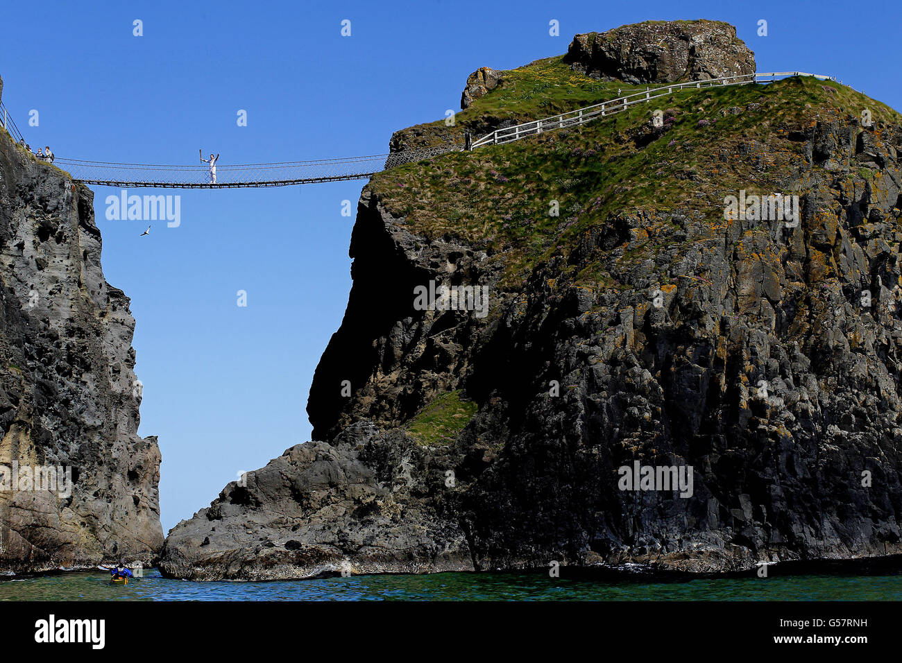 La flamme olympique traverse le célèbre point de repère du pont de corde Carrick-a-Rede à l'extérieur du village de Ballintoy, au Co.Antrim, par le porteur Denis Broderick. Banque D'Images