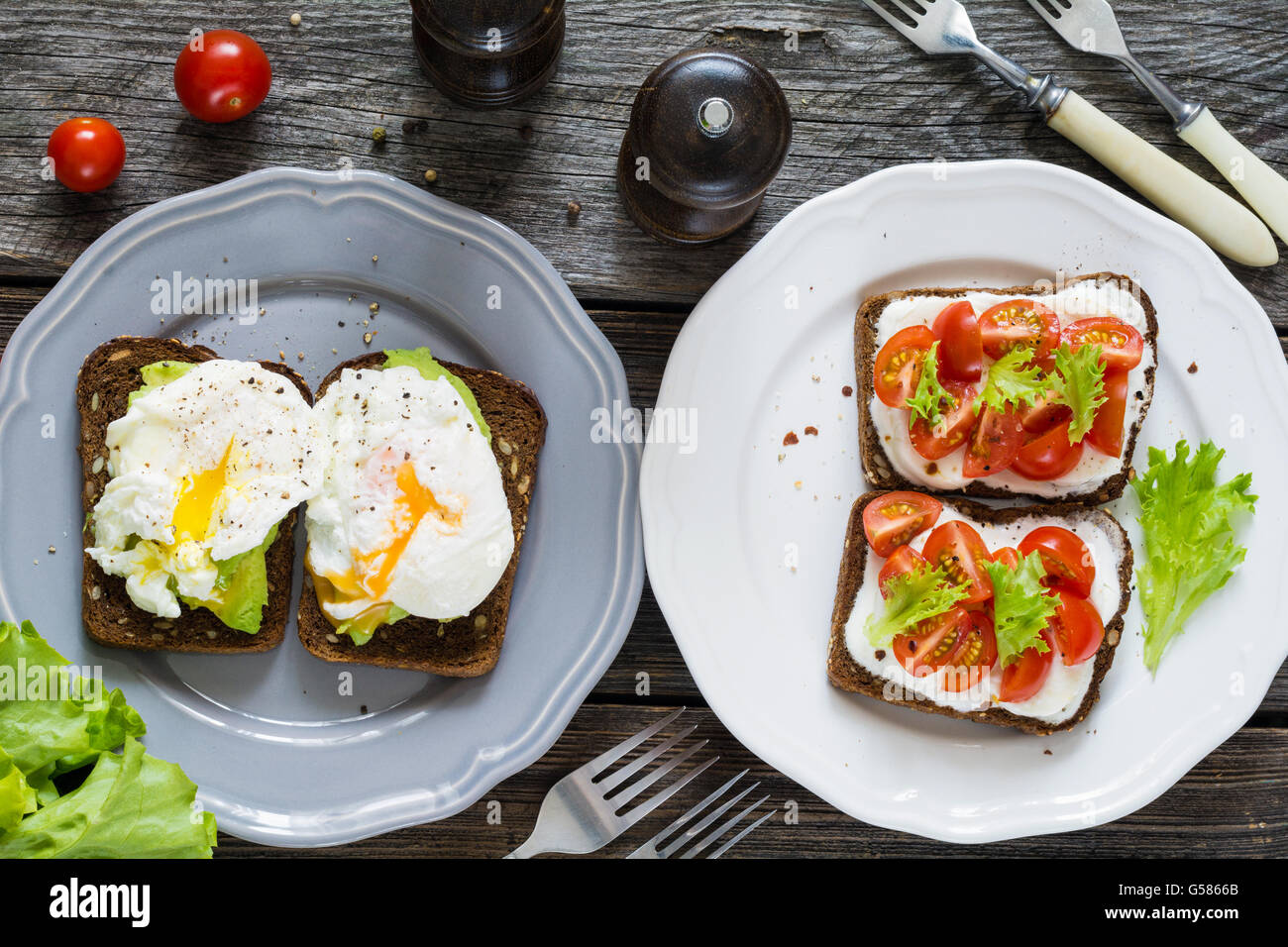 Divers toasts sain : oeuf poché, avocat, fromage frais, tomates, basilic et salade. Assiette de collations santé Banque D'Images