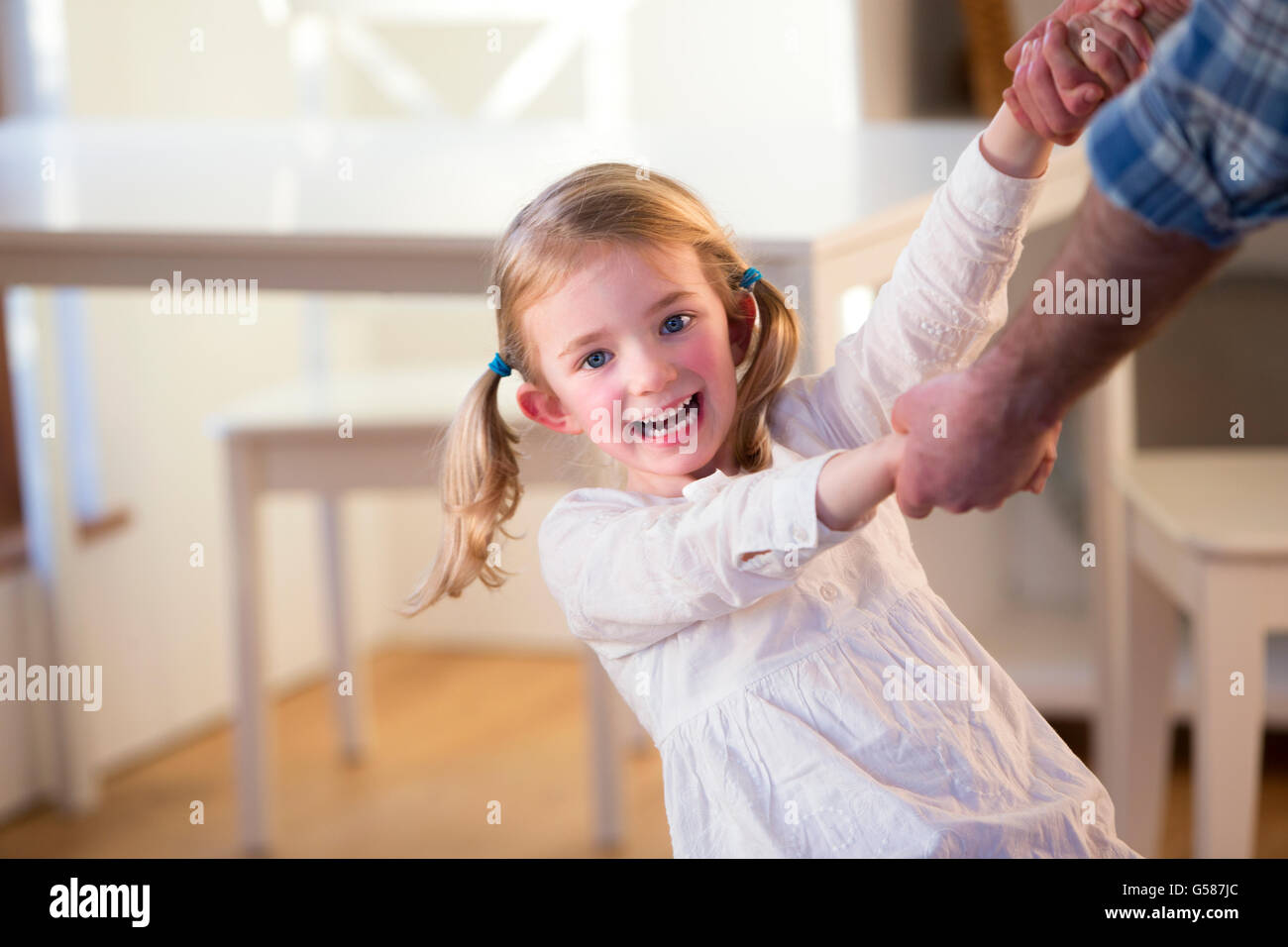 Petite fille danser et tourner avec son père à la maison Banque D'Images