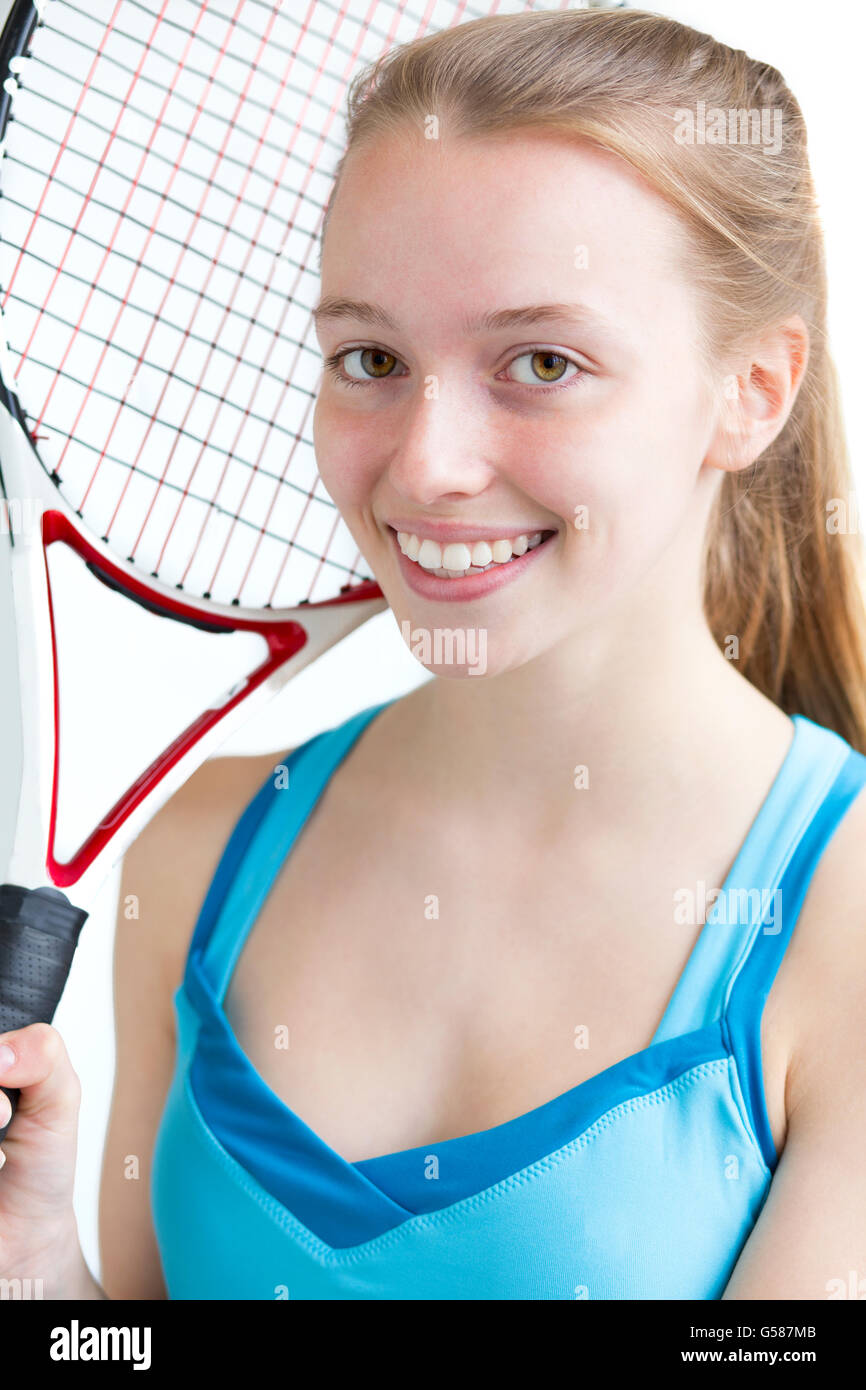 Portrait d'une jeune fille prête à jouer au tennis. Elle est tenue d'une raquette et smiling for the camera Banque D'Images