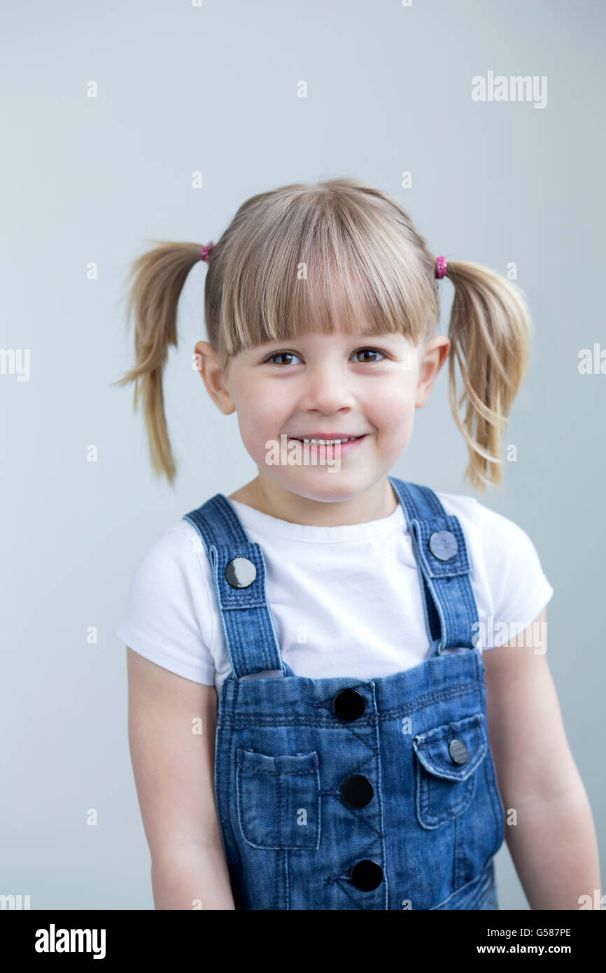 Cute young girl en salopette smiling at the camera Banque D'Images