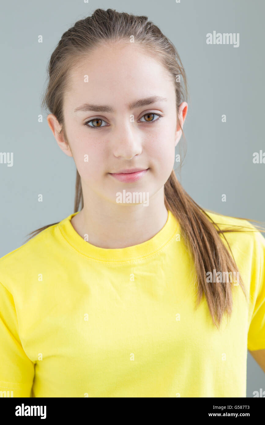Gros plan d'une jeune fille. Elle porte un tshirt jaune et est à la recherche de l'appareil photo. Banque D'Images