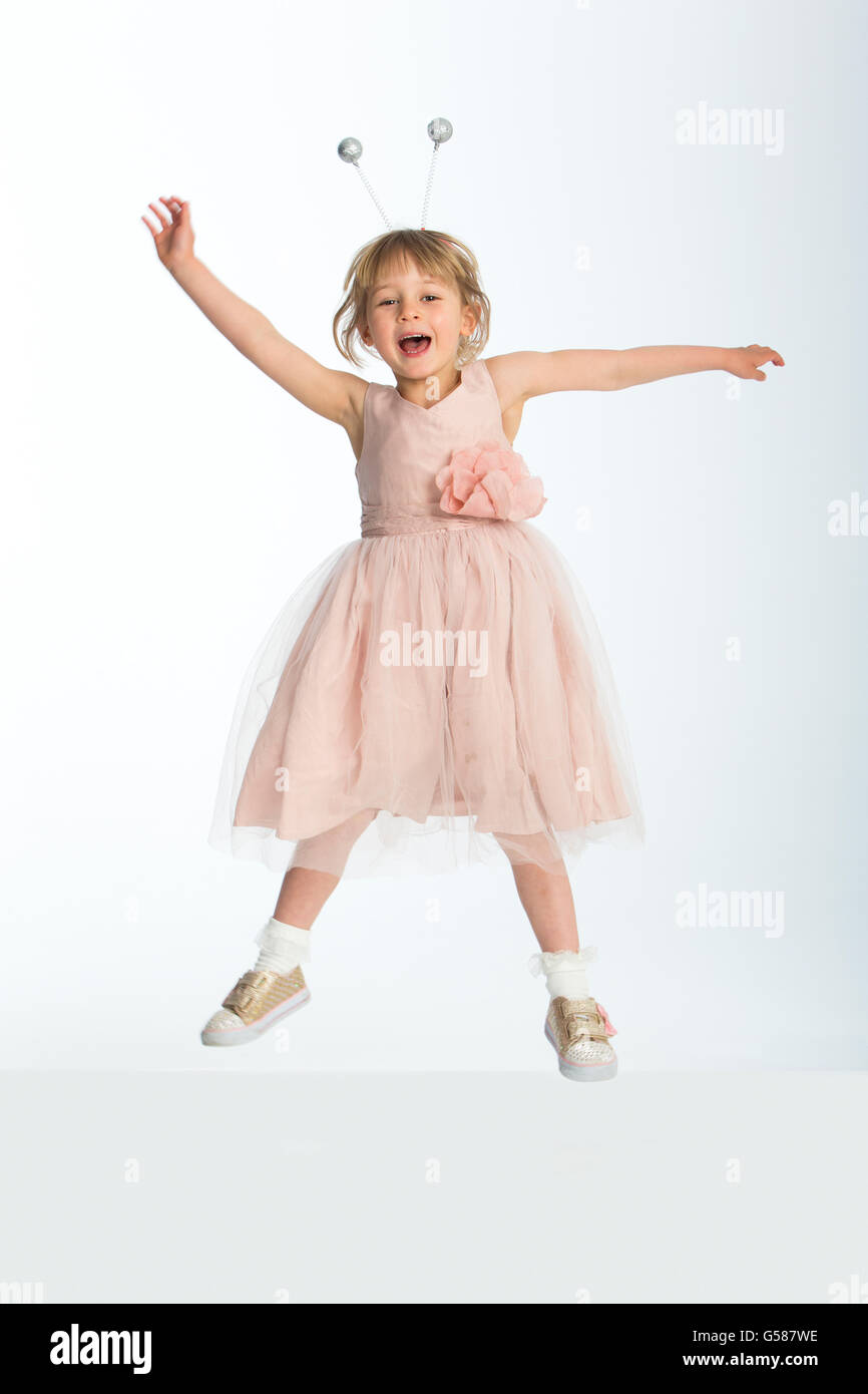 Cute little girl porte une robe et bourdon boppers posant dans les airs sur un fond blanc. Banque D'Images