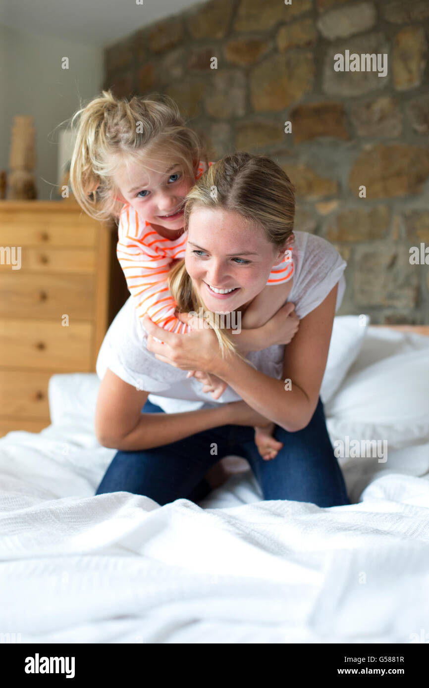 Mère et fille jouer sur un lit à la maison Banque D'Images