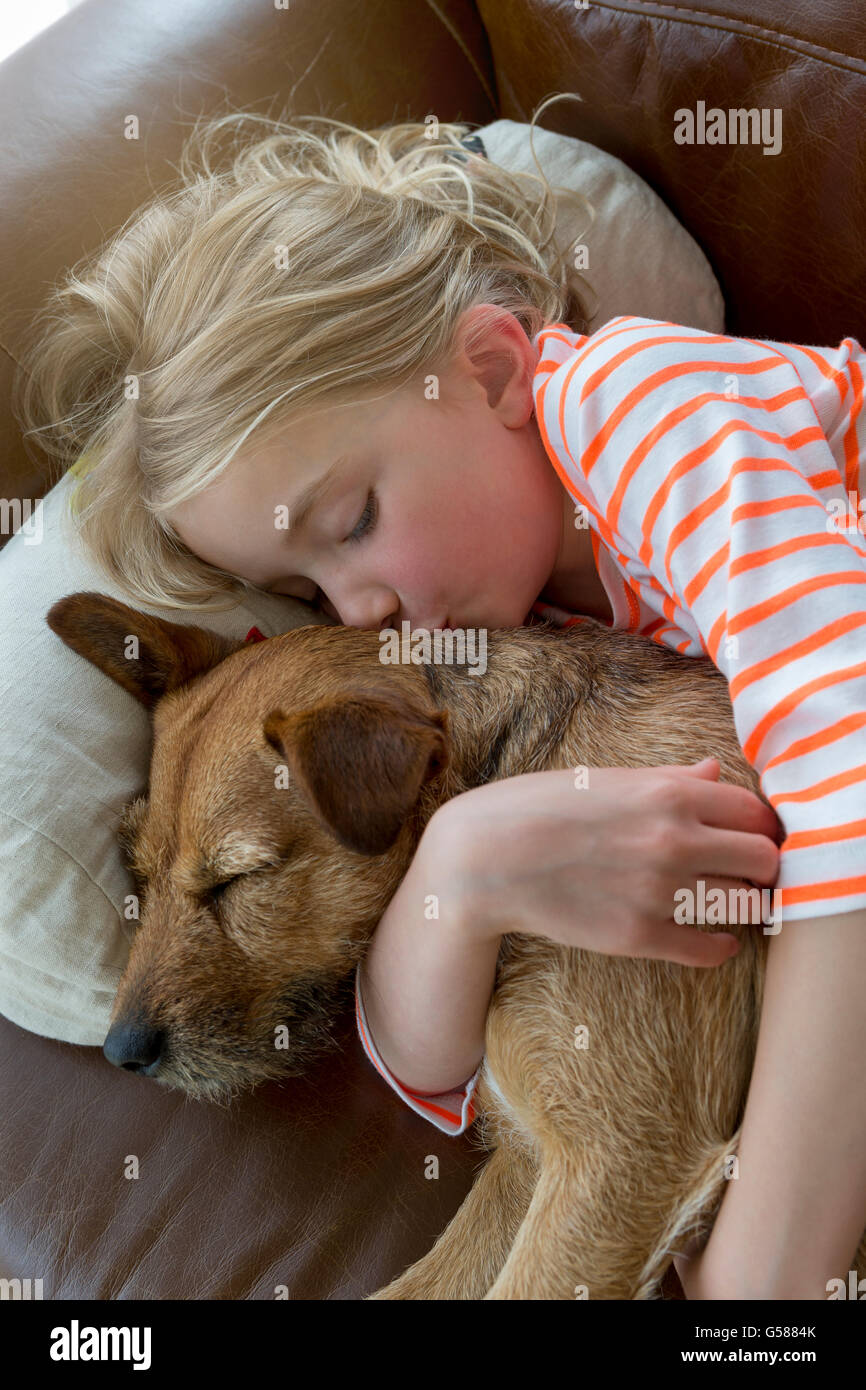 Jeune fille de câliner son chien sur un canapé à la maison. Banque D'Images