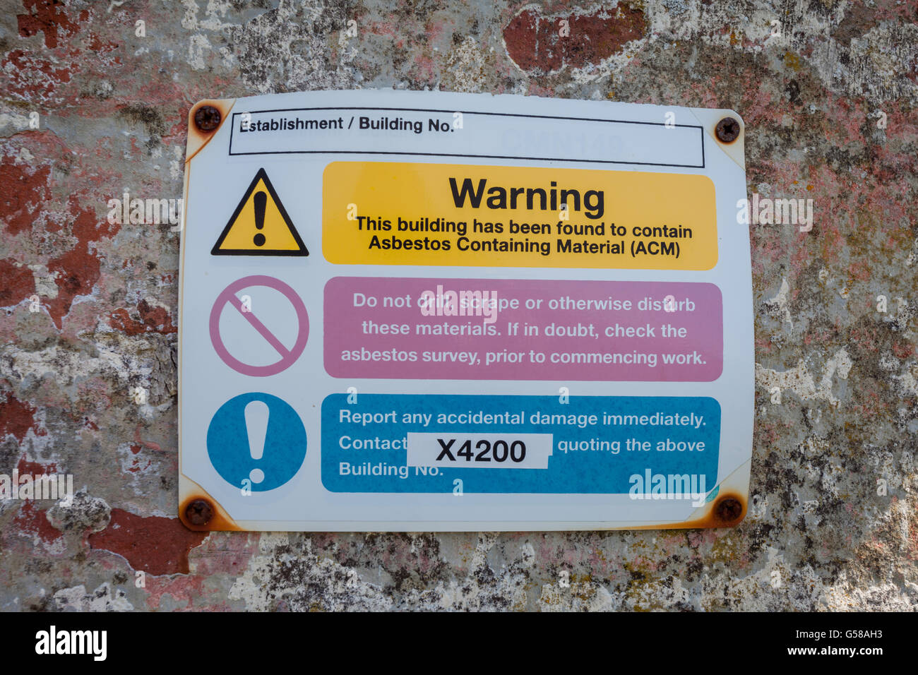 Inscrivez-vous sur le mur extérieur d'un bâtiment montrant un avertissement que le bâtiment contient de l'amiante. Banque D'Images