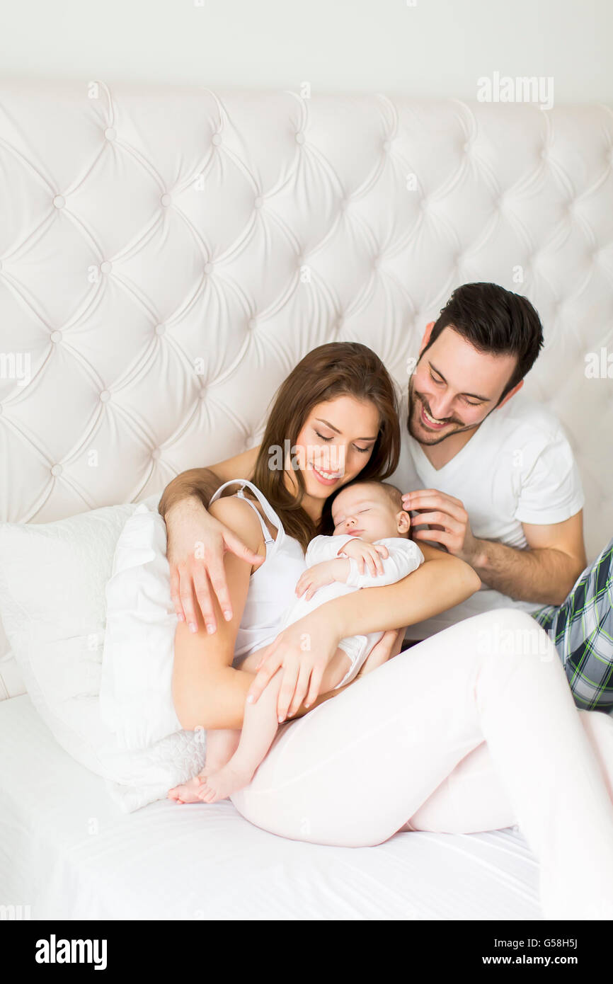 Famille heureuse avec bébé nouveau-né sur le lit de la chambre Banque D'Images