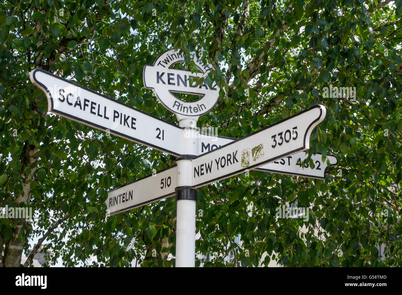 Poteau de signalisation en centre-ville de Windermere Cumbria jumelée avec Rinteln Rinteln allemand distances à New York l'Everest Scafell Pike Banque D'Images