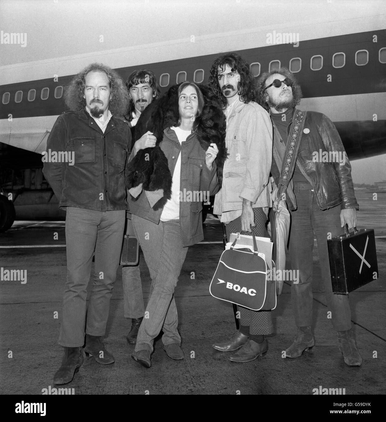 Groupe de rock américain The Mothers of invention, photographié à l'aéroport d'Heathrow après avoir pris l'avion de New York. Ils se décrivent comme des travailleurs sociaux chanteurs. Il s'agit de (l-r) Ray Collins, Jimmy Carl Black, Suzie creamcheese, Frank Zappa et Don Preston. Les mères de l'invention sont le premier groupe de freak-out de l'Amérique et sont ici pour un concert d'une nuit au Royal Albert Hall quand ils seront augmentés par les membres de l'Orchestre Philharmonique de Londres. Ils ont un nouveau disque simple, 'Big Leg Emma', et un L.P. « Absolutely Free » est prévu pour la sortie d'octobre. Zappa écrit toutes les paroles. Banque D'Images