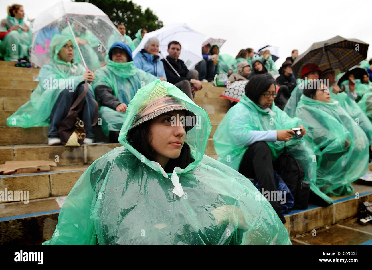 Les fans de tennis se réfugient à l'abri de la pluie sur Murray Mount pendant le septième jour des Championnats de Wimbledon 2012 au All England Lawn tennis Club, Wimbledon. Banque D'Images
