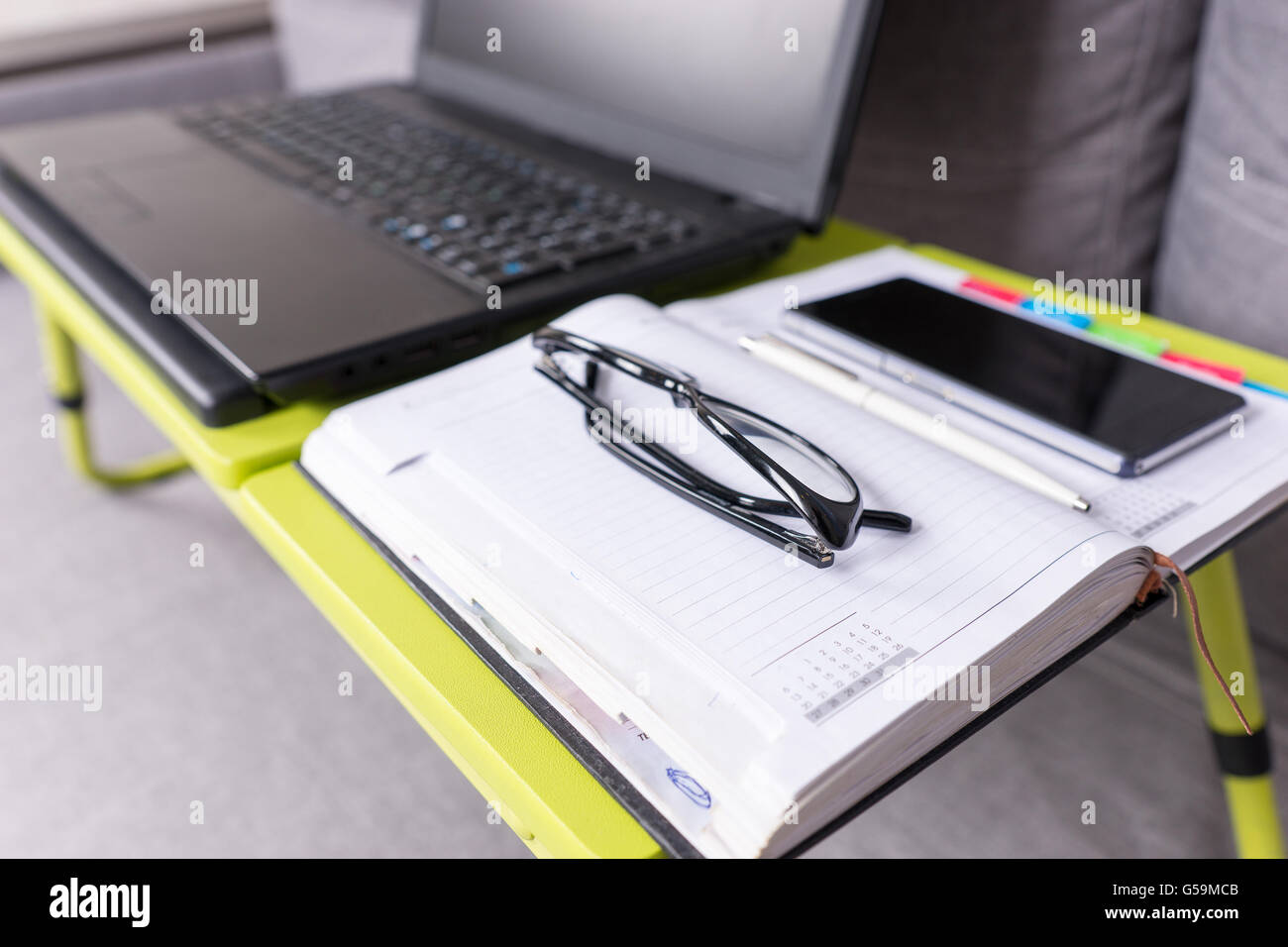 Se concentrer sur des verres se trouvant sur la table ordinateur portable à proximité d'une page vierge d'un journal intime avec un stylo pour prendre des rendez-vous, organiser un planning. Banque D'Images