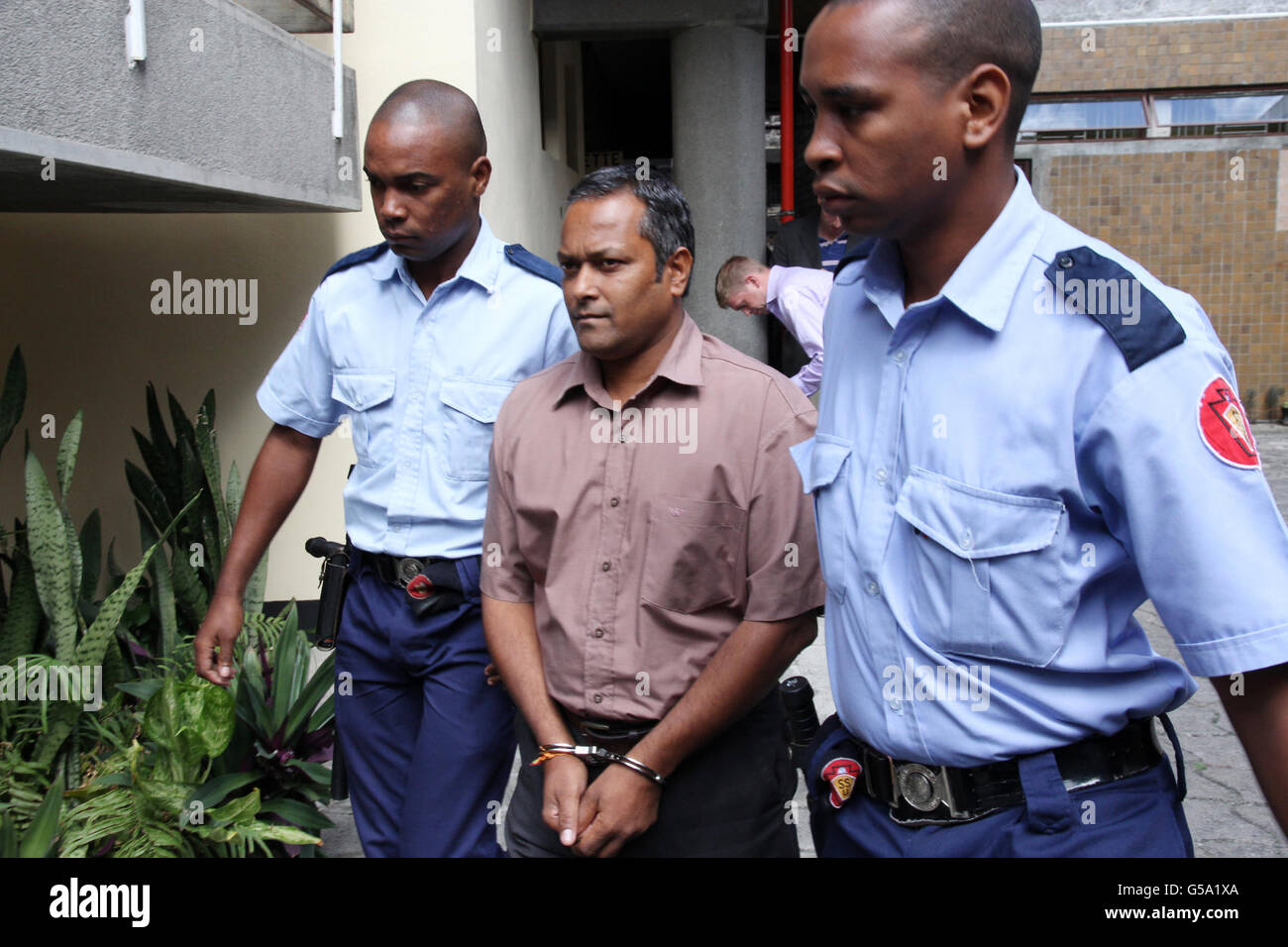 Sandip Mooneea accompagné d'officiers de l'SSU arrive à la Cour suprême de Port Louis, à l'île Maurice, alors que Sandip Moneea et Avinash Treebhoowoon, accusés du meurtre de la citoyenne irlandaise Michaela McReavey, qui a été tuée pendant sa lune de miel il y a un an. Banque D'Images