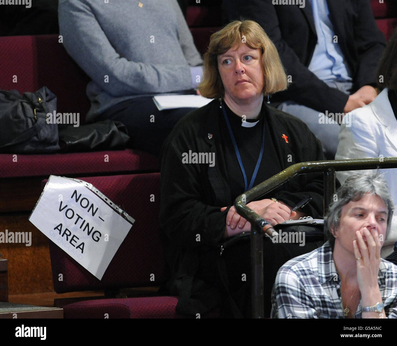 Une femme membre du clergé siège dans le public pendant les discussions sur l'introduction des femmes évêques qui se tiennent au Synode général à Central Hall, à l'Université de York. Banque D'Images