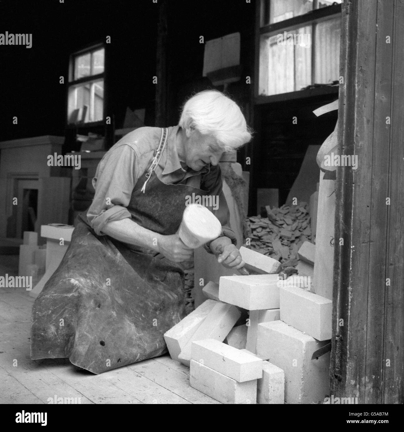 M. Jim Strange, 72 ans, est un expert en pierre, car sa famille s'est mise en carrière dans les Cotswolds depuis des siècles.Ici, il façonne la pierre pour la construction de maisons dans les carrières de Campden, Gloucestershire. Banque D'Images