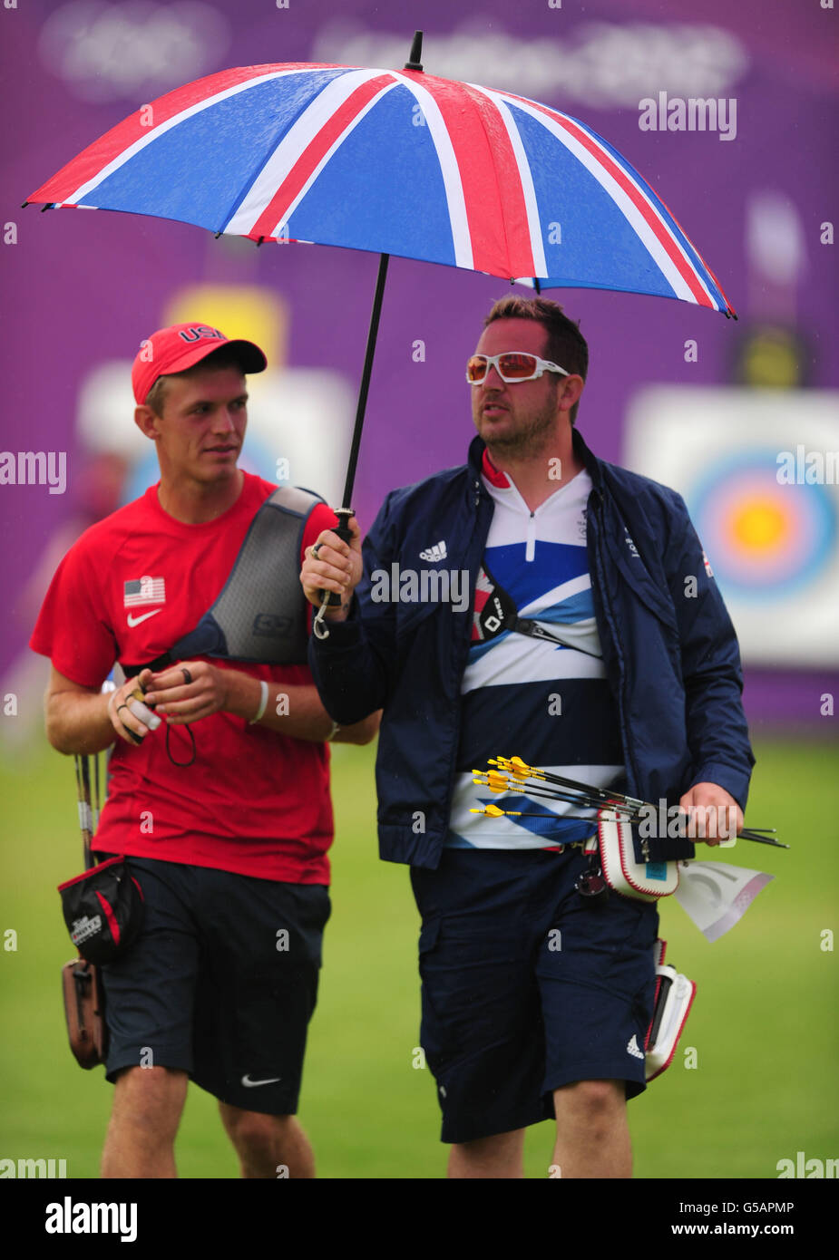 Larry Godfrey (à droite), en Grande-Bretagne, revient à sa position de tir avec Jacob Wukie (à gauche) des États-Unis tenant un parapluie pendant le Round de tir à l'arc individuel des hommes au terrain de cricket Lords, à Londres. Banque D'Images