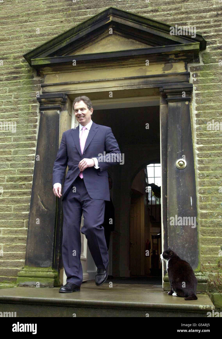 Le Premier ministre britannique Tony Blair attire l'attention de Thomas le chat, alors qu'il sort du Bronte Parsonage, Howarth, lors d'une visite d'une journée dans le Yorkshire pour stimuler le tourisme britannique après le saut à pied et à la bouche. Banque D'Images