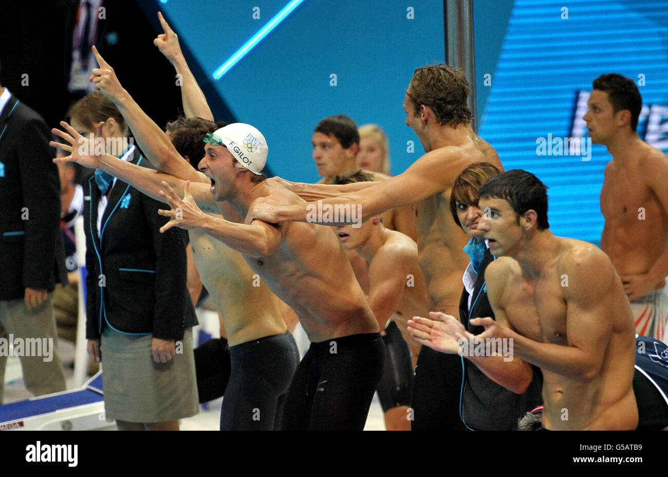 L'équipe française célèbre la médaille d'or devant Michael Phelps (à droite) et l'équipe américaine en argent dans le relais Freestyle 4 x 100 m au centre aquatique de Londres. Banque D'Images