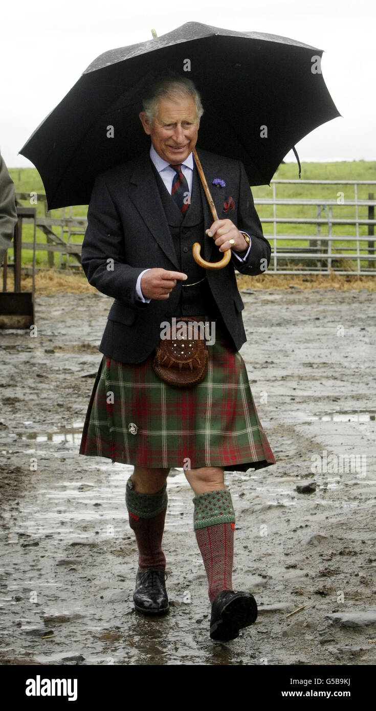 Le Prince de Galles s'abois sous un parapluie lors d'une visite à la ferme Sibster près de Wick en Écosse. Banque D'Images