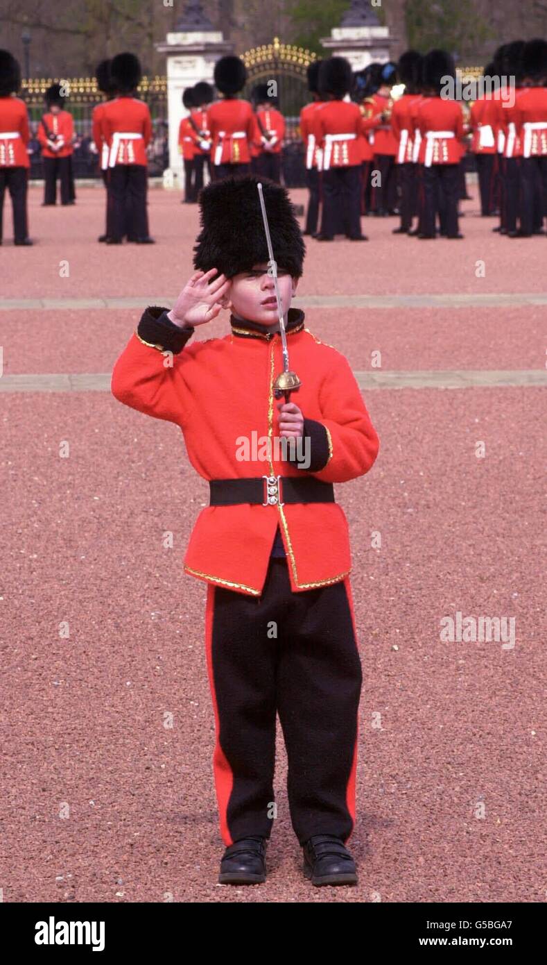 Matthew Swallow, six ans, porte fièrement un uniforme de garde sur la piste de Buckingham Palace - la résidence officielle de Londres de la reine Elizabeth II - alors que la cérémonie de la relève de la garde se poursuit derrière lui. *... Matthew, de Potters Bar, Hertfordshire, était à l'extérieur du Palais, attendant d'être photographié dans le cadre d'un projet scolaire, quand les officiels royaux l'ont repéré et l'ont amené à l'intérieur pour une vue de la tribune. Banque D'Images